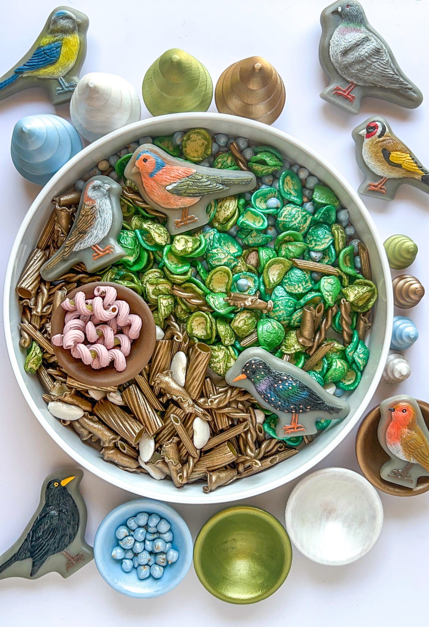 A collection of double-sided sensory play stones shaped like various birds, displayed with other natural playdough and sensory bin fillers. Hippie hooray chickpea and chunky pasta sensory bin filler